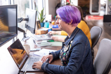 employee on laptop with purple hair